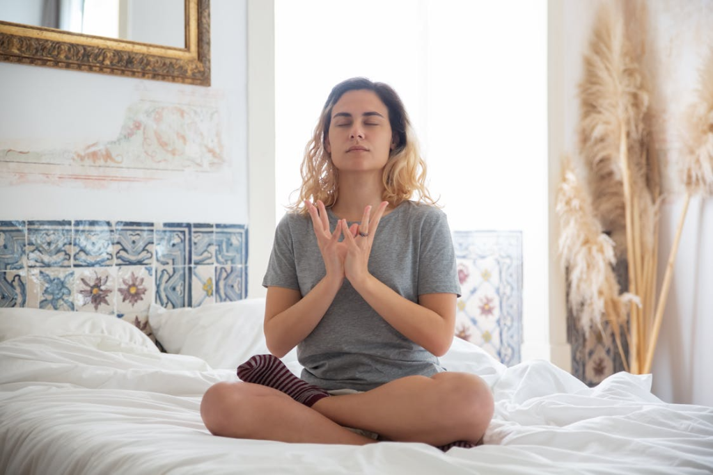 A woman on a bed sitting silently with eyes closed