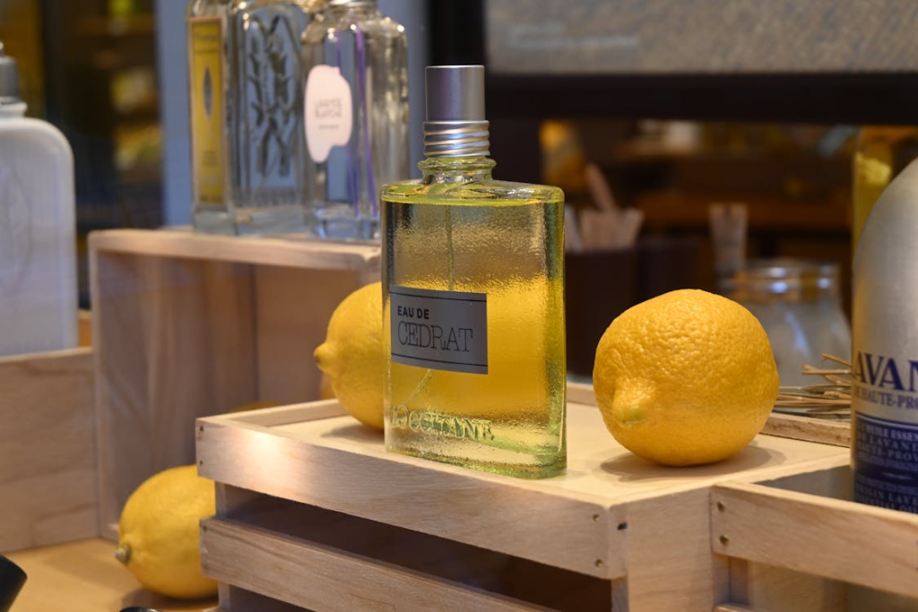 A bottle of citrus perfume kept on a table with whole lemons on the side