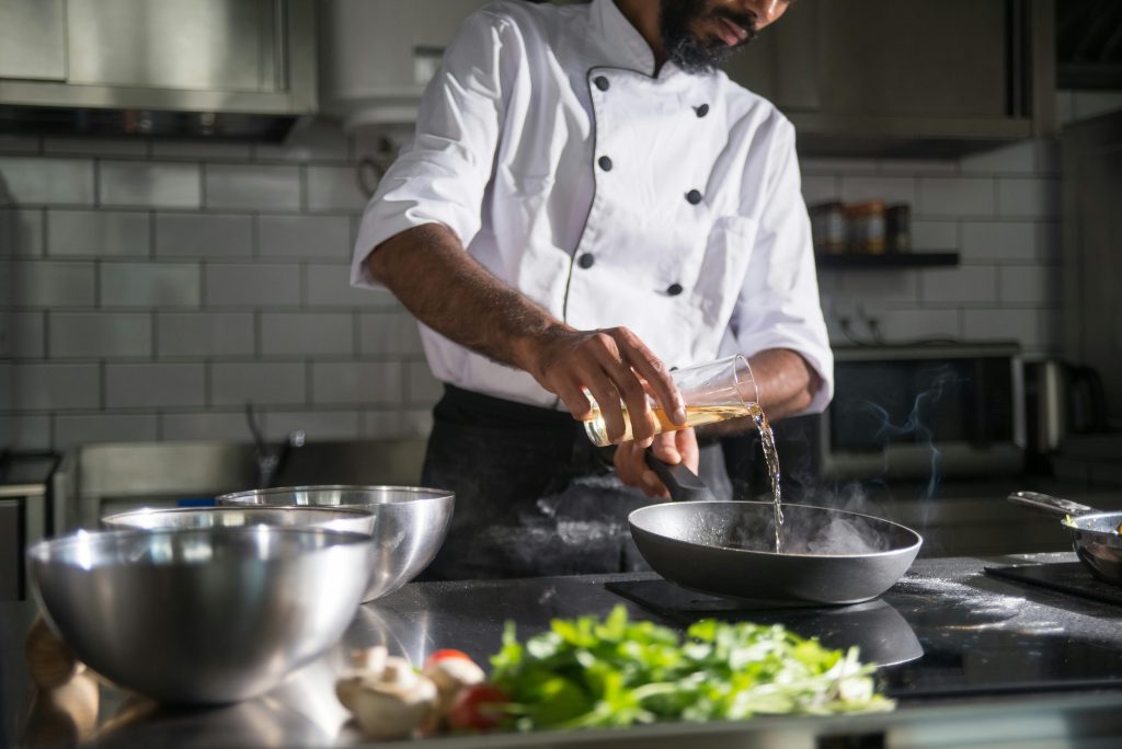 a professional chef preparing food in the kitchen using cold-pressed oil