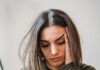 WhatsApp Woes: An Overthinker’s Guide to Text Ghosting A young woman sitting on a couch, looking down at her glowing smartphone screen with a subtle expression of sadness and anxiety, waiting for a reply.