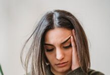 WhatsApp Woes: An Overthinker’s Guide to Text Ghosting A young woman sitting on a couch, looking down at her glowing smartphone screen with a subtle expression of sadness and anxiety, waiting for a reply.