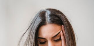 WhatsApp Woes: An Overthinker’s Guide to Text Ghosting A young woman sitting on a couch, looking down at her glowing smartphone screen with a subtle expression of sadness and anxiety, waiting for a reply.