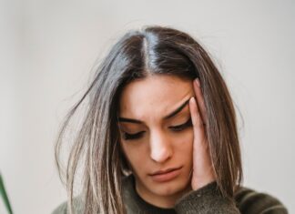 WhatsApp Woes: An Overthinker’s Guide to Text Ghosting A young woman sitting on a couch, looking down at her glowing smartphone screen with a subtle expression of sadness and anxiety, waiting for a reply.