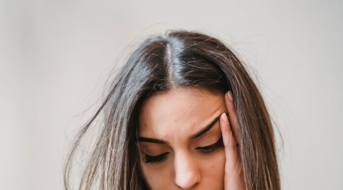 WhatsApp Woes: An Overthinker’s Guide to Text Ghosting A young woman sitting on a couch, looking down at her glowing smartphone screen with a subtle expression of sadness and anxiety, waiting for a reply.